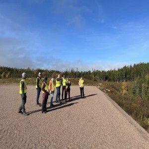 Hélène accompagnée d'un groupe de travailleurs sur une route entourée de forêt