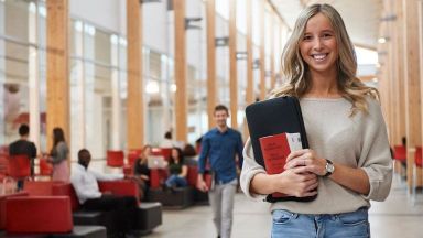 une étudiante souriante avec un livre dans les bras